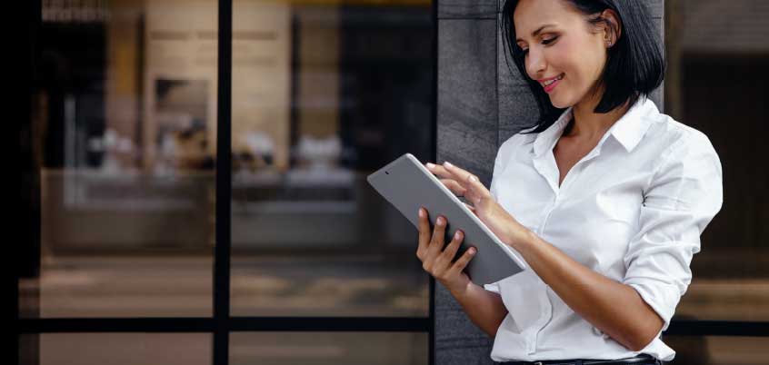 woman using tablet outside of office building