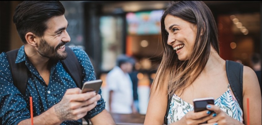 Man and woman on phones eating food.