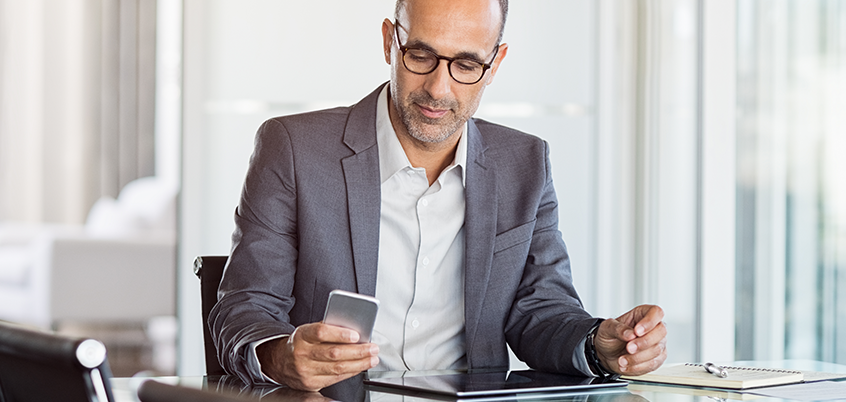 Man in office looking at phone.