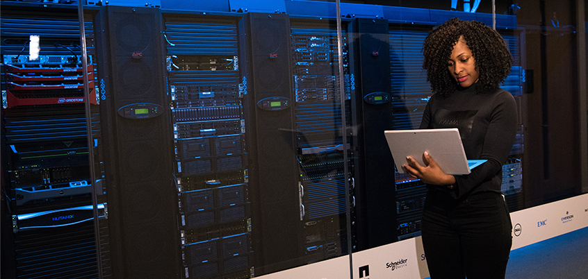 Woman on laptop in front of servers.
