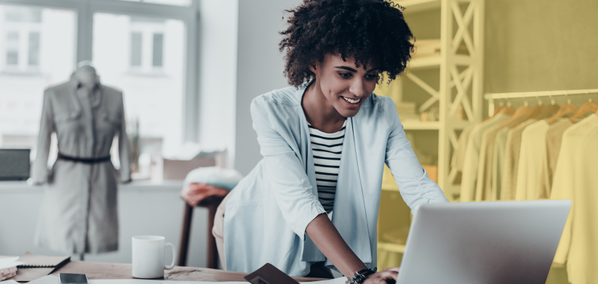 Woman in retail setting working on laptop.