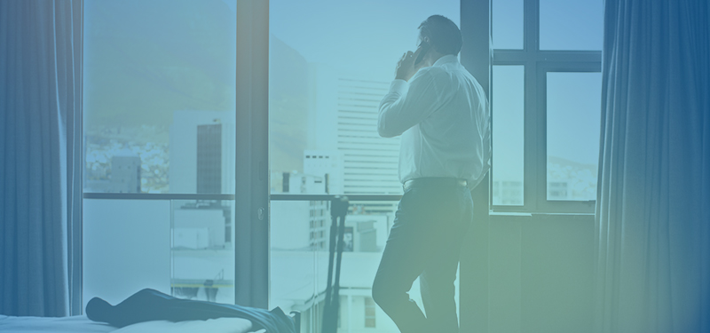 man looking out hotel room window