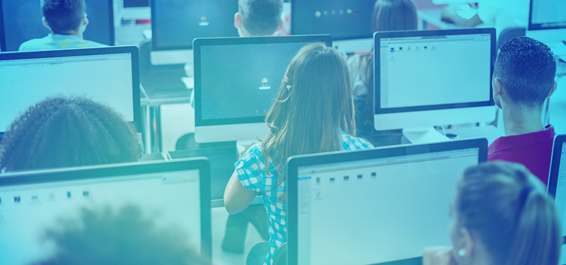 Classroom full of children looking at computer monitors