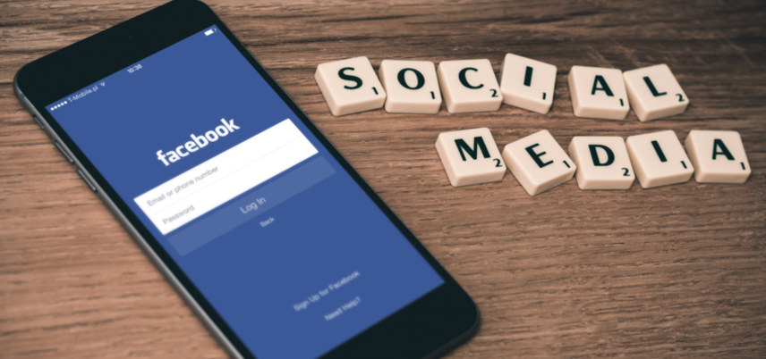 smartphone showing Facebook and social media spelled out with scrabble tiles