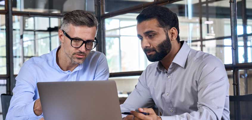 two men looking at a laptop