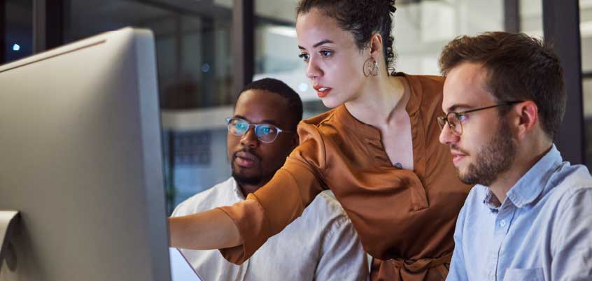 woman and two men looking at computer monitor