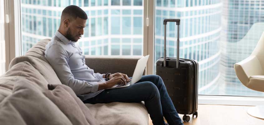 man sitting on couch in hotel room using laptop
