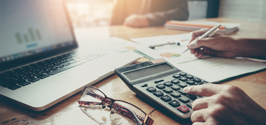 Person working at desk with laptop and calculator