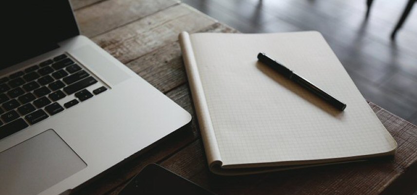closeup of laptop and notebook on cafe table