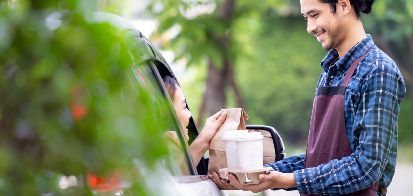 Man bringing coffee to customer at their car