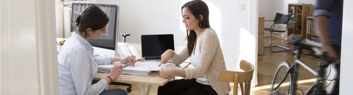 Two women at table looking at papers