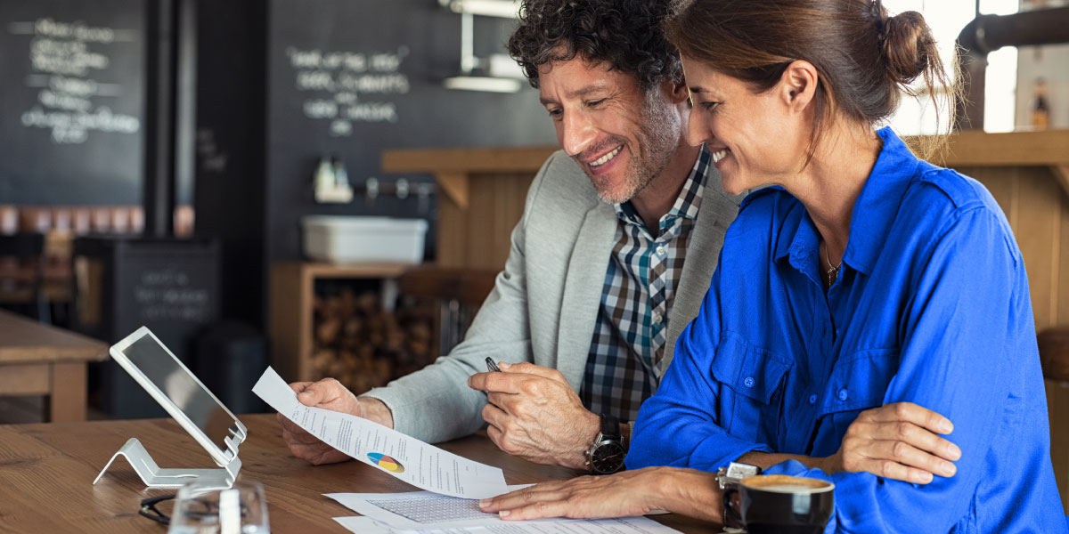 Man and and woman looking at papers and tablet