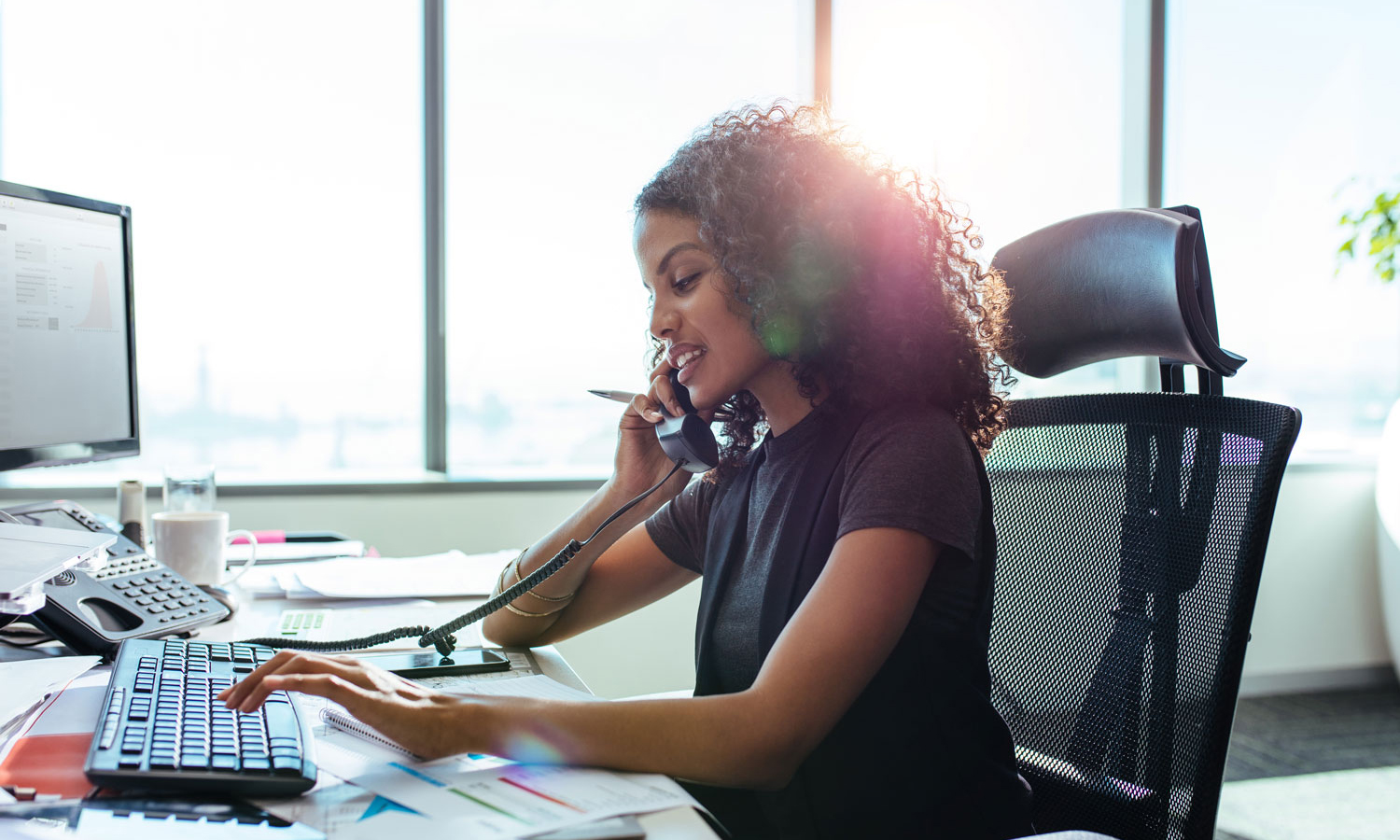 Woman in her office on phone and working on computer