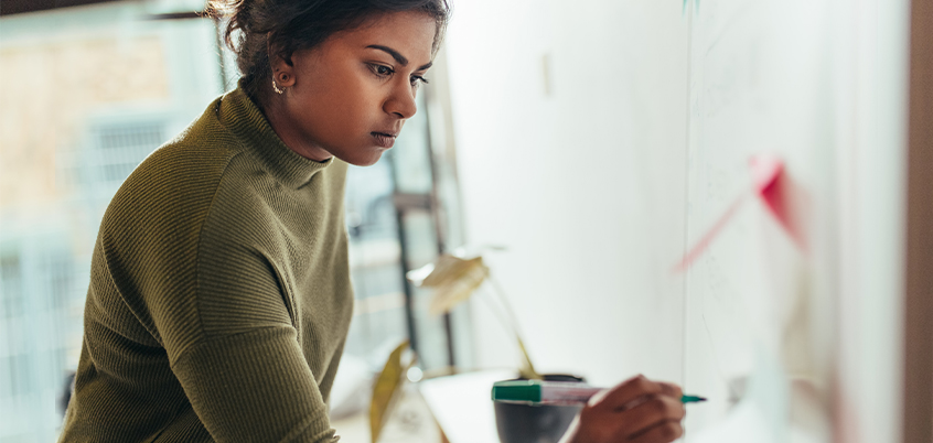 Woman in office writing on a white board