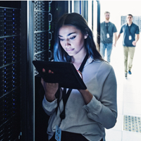 woman on tablet standing in front of server racks