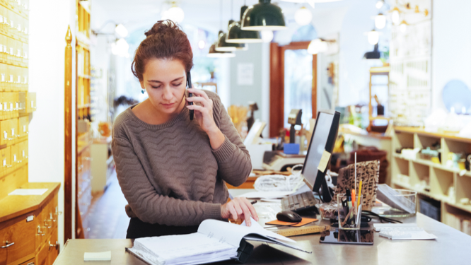 Small business owner looking at records while talking on the phone